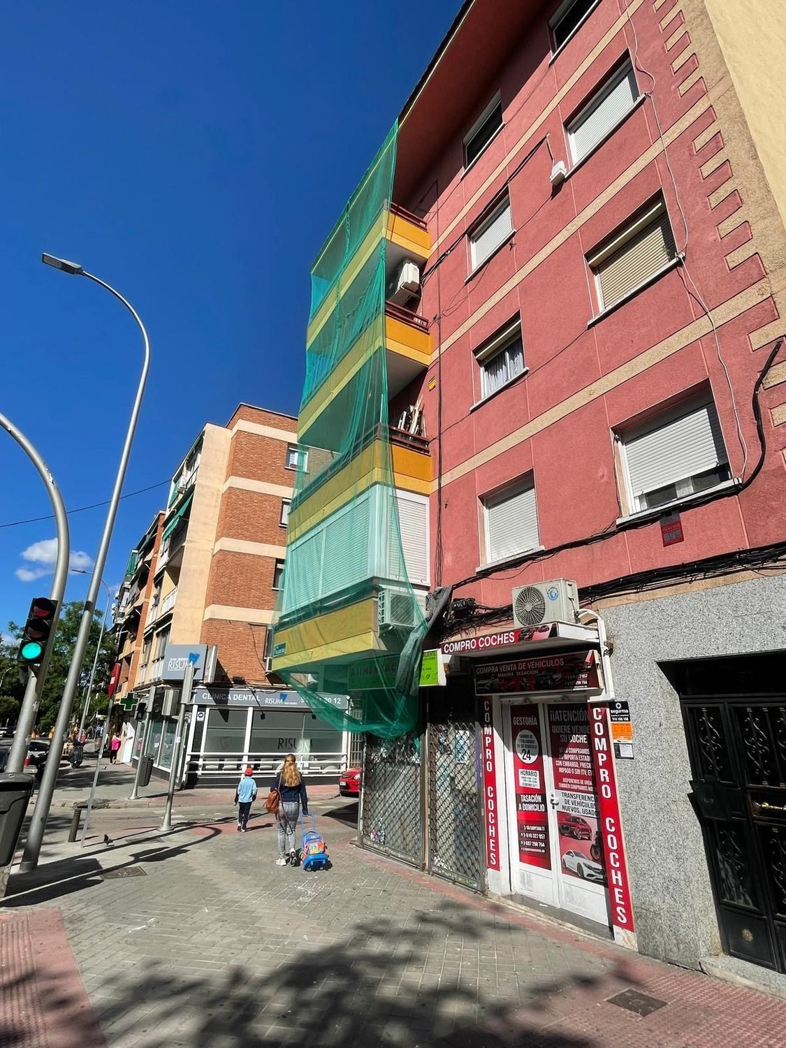 Fachada de comunidad de vecinos antes de pintar, con el revestimiento rojo antiguo
